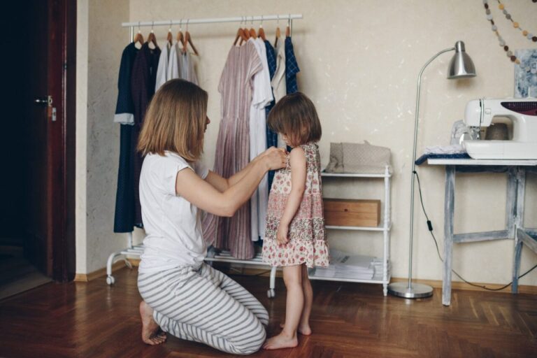 Parent comparant deux tailles de vêtements pour enfant dans un magasin Okaïdi.